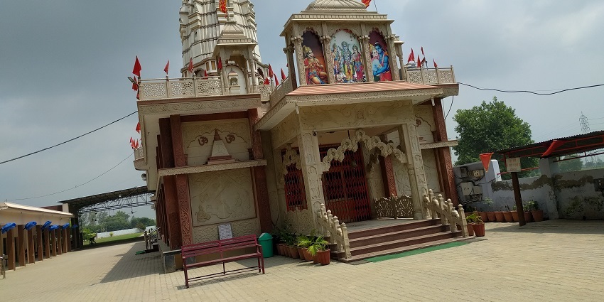 The image depicts a Hanuman Temple with a traditional architectural style, featuring intricate stone carvings.