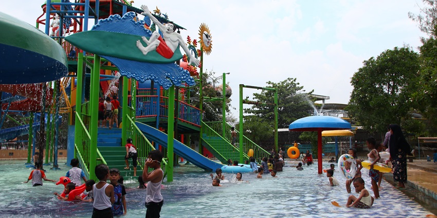 View of amusement and water park kids playing in the water and rides during day time