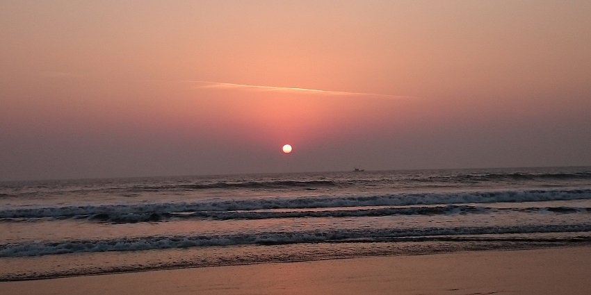 Scenic Harihareshwar Beach with black sand and spiritual significance.