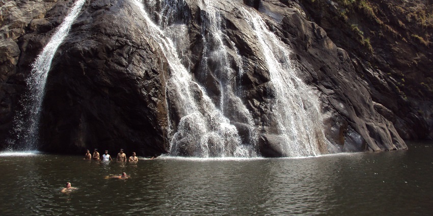 A stunning waterfall cascading from a height, surrounded by lush greenery and rocky cliffs, one of the best places to visir near Arambol.