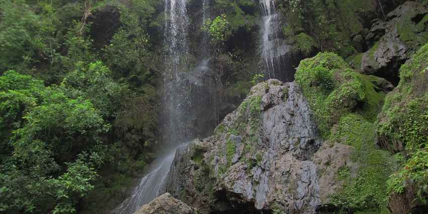 Image of Hathni waterfalls are surrounded by lush greenery, water cascading through rocks
