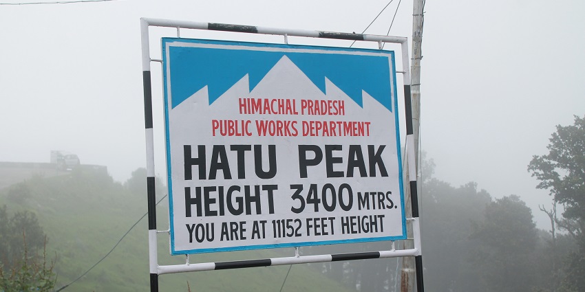 Hatu Peak with its lush green slopes and a clear sky adorned with fluffy white clouds