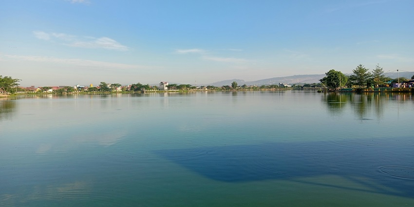 Image of lake with serene water, clear blue sky and lush green trees are surrounded by the lake