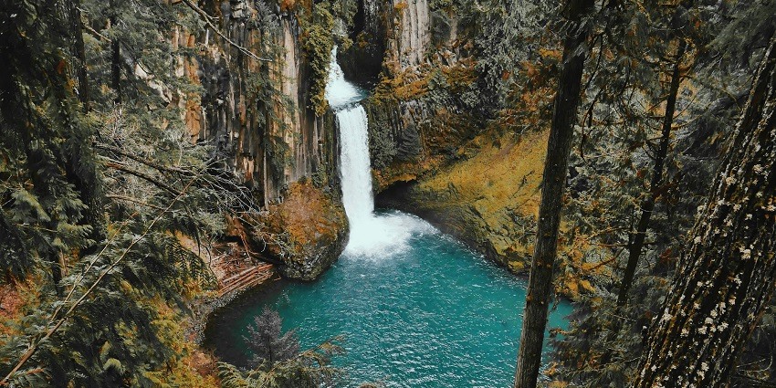The water cascades through the cliffs surrounded by greenery.