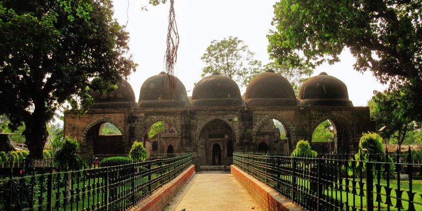 An expansive view of the Hilal Khan Masjid surrounded by lush greenery and distinctive minarets