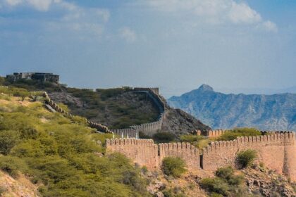 A breathtaking view of Ajmer surrounded by lush green meadows and a body of water.