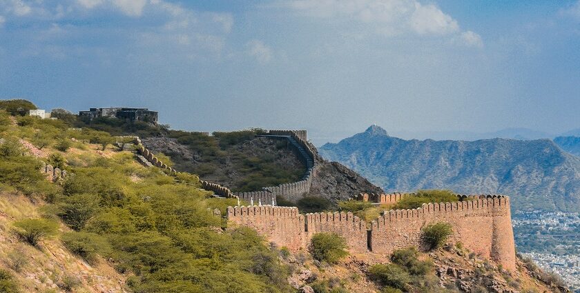 A breathtaking view of Ajmer surrounded by lush green meadows and a body of water.