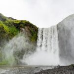 Image of waterfall cascading through lush green rocks - explore Hivre Waterfalls