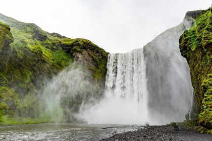 Image of waterfall cascading through lush green rocks - explore Hivre Waterfalls