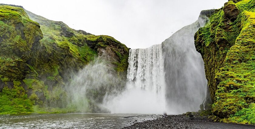 Image of waterfall cascading through lush green rocks - explore Hivre Waterfalls