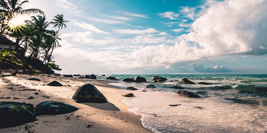 A picture of a beach taken during daytime with the rocks and pebbles visible at the shore