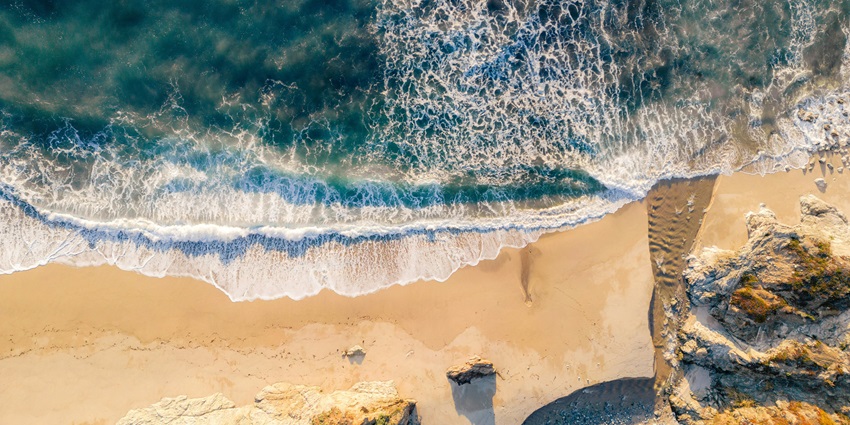 Aerial view of a beach featuring crystal-clear waves, and breathtaking scenery