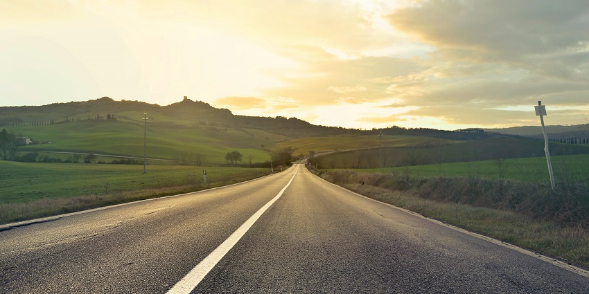 A breathtaking view of a road leading upto lush green mountains during the daytime.
