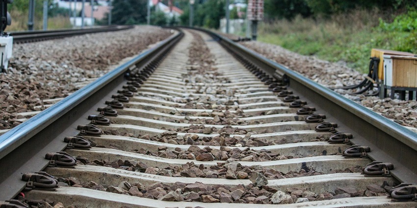 A stunning view of a railway track with small rocks around greenery during the daytime.