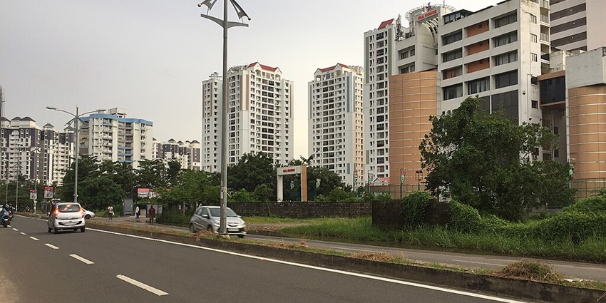 Image of Link Road in Kochi with tall buildings and busy cars on the road