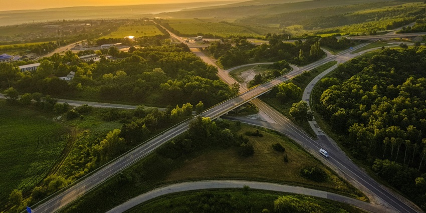 Aerial view of roadways with flyovers and lush green surrounding under clear sky