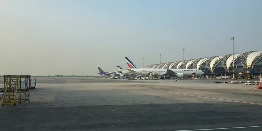 A stunning view of a few aircraft standing on an airport in front of architecture.