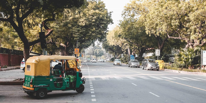 Image of local auto on the street surrounded by trees and building under clear sky