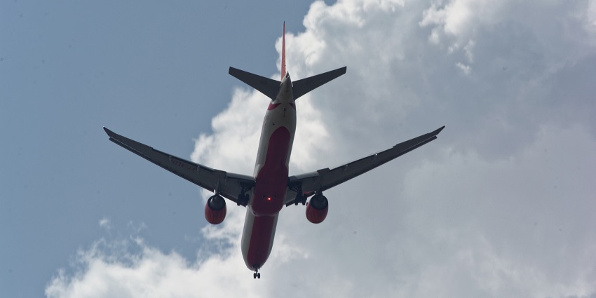 An aeroplane flying against a clear blue sky for Narsinghgarh Wildlife Sanctuary.