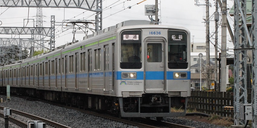 A Tobu Railway train traveling through scenic countryside in a beautiful city.