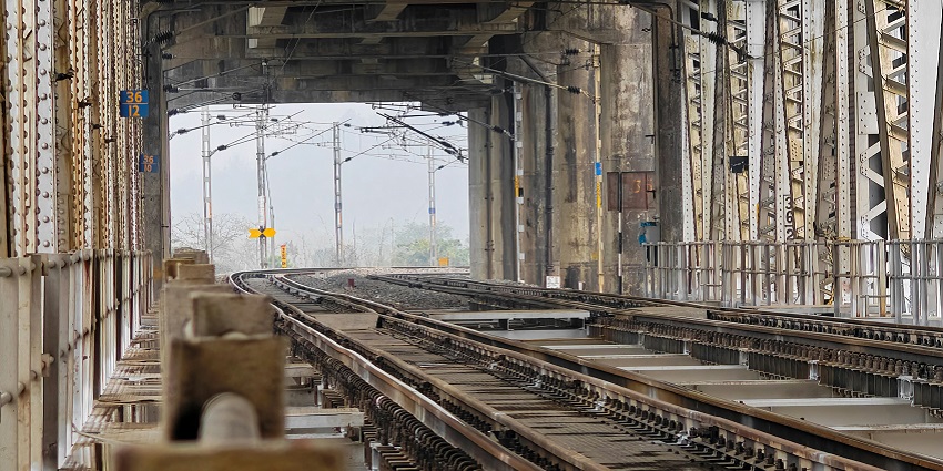 An image showing railway tracks going through lush green mountains during day time