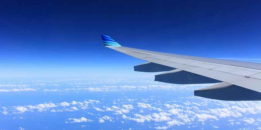 A breathtaking view of a clear blue sky with dense clouds from an aeroplane window.