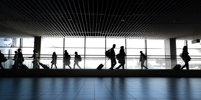 A picture of an airport with people commuting towards the flight terminals