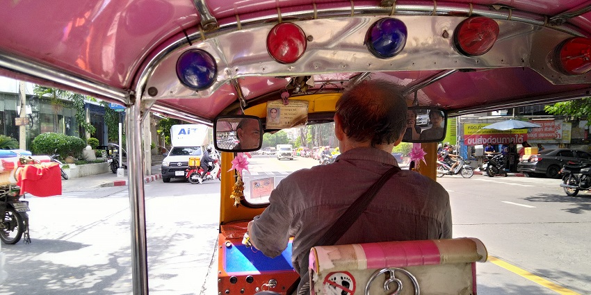 A person riding a tuk-tuk through the vibrant streets for reaching Heritage Transport Museum.