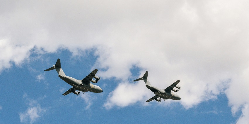 A breathtaking view of two grey aeroplanes in the clear blue sky during the daytime.