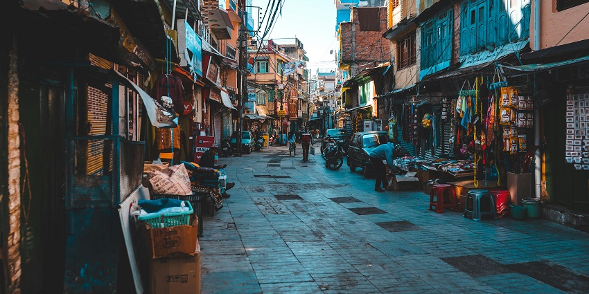 A view of the street during the evening, with shops on either side.