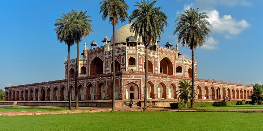 A picture of a historical monument built in traditional Mughal architecture, with a huge garden in front