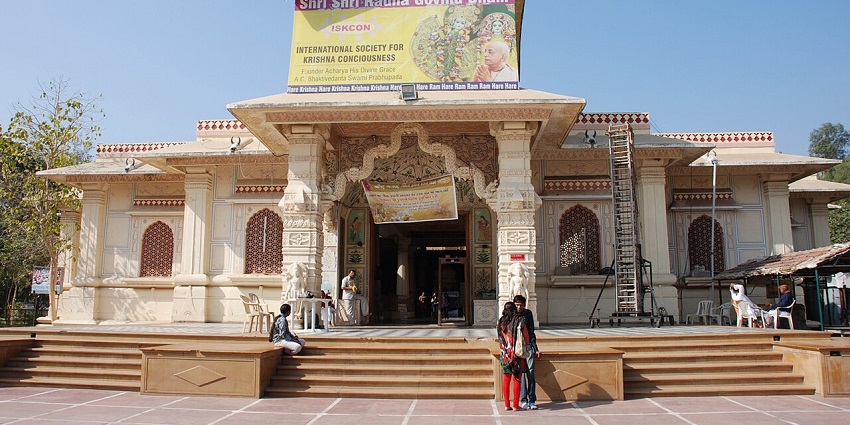 Front view of the temple, with intricately carved pillars and devotees walking in