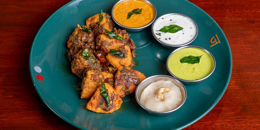 A plate of assorted food including grilled meat, vegetables, and a side of dipping sauce.
