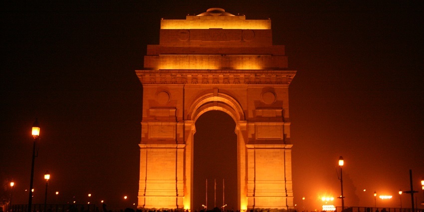 A picture of India Gate taken during night time with multiple lights illuminating the monument