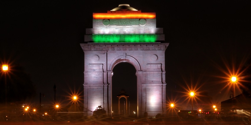 A picture of the India gate clicked at night with the Indian tricolour displayed over it