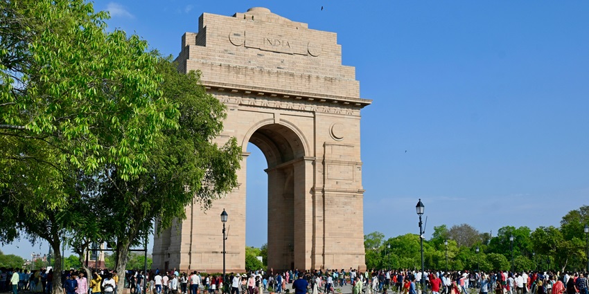 Scenic view of India Gate, New Delhi surrounded by green grass and people exploring