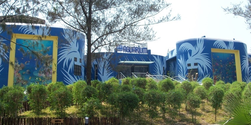 The entrance of the aquarium surrounded by tall trees and shrubs