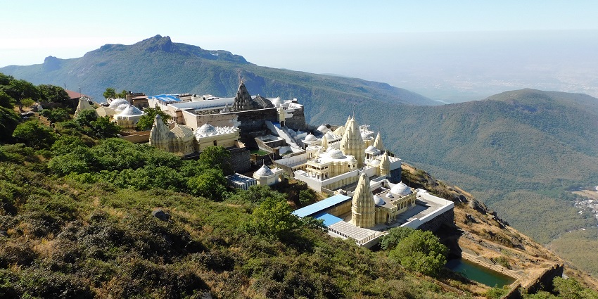 Aerial view of Jain Temples on Girnar Peak amidst the lush greenery and majestic forest range