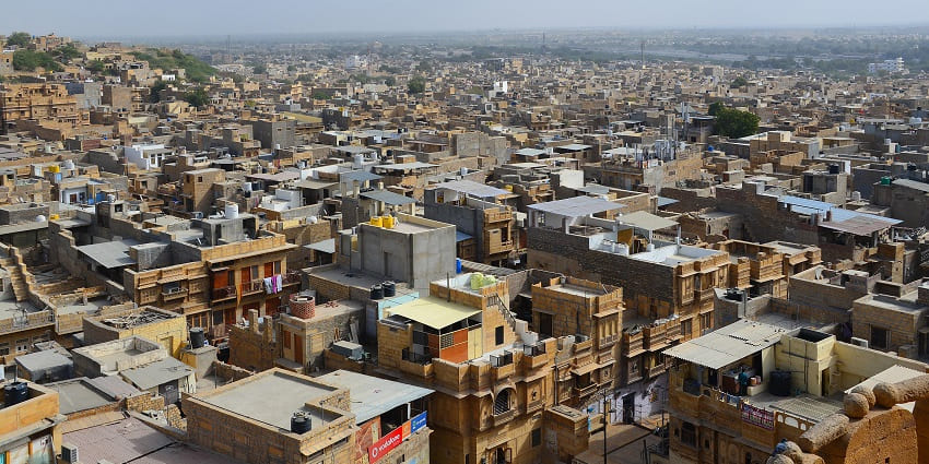 Jaisalmer city with golden buildings stretching across a dry landscape under a hazy sky