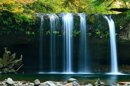 Serene lake with a cascading waterfall, captured in a long exposure during the daytime