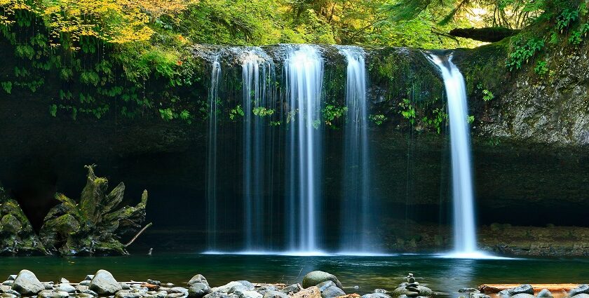 Serene lake with a cascading waterfall, captured in a long exposure during the daytime