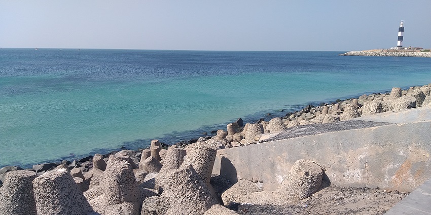 The spectacular view of a lighthouse and the Arabian sea from the beach.