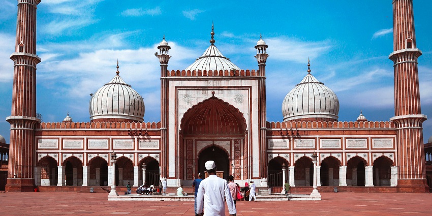Image of a man walks in front of a Jama Masjid, showcasing beautiful architecture.