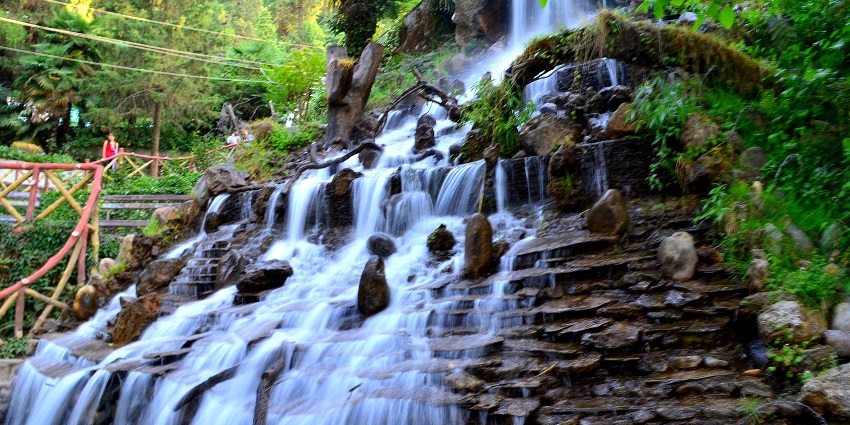 A picture of a waterfall cascading down a rocky hill and forming a beautiful pond at the base