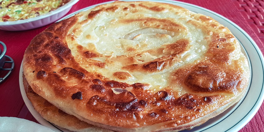 A picture of a delicious paratha thali served at a restaurant in Rajkot with pickle and mint chutney