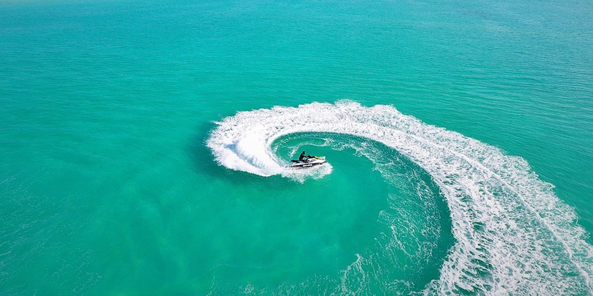 Aerial view of someone jet skiing in the clear turquoise waters of the beach