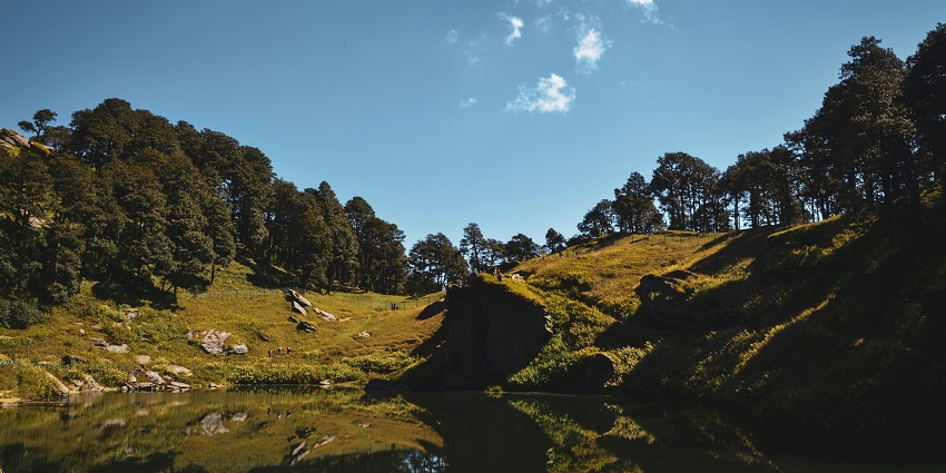 Picturesque view of a lake surrounded by a lush green hillside - one of the best hill station near Anandpur Sahib