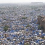 Panoramic view of Jodhpur's cityscape with forts and blue-painted buildings.