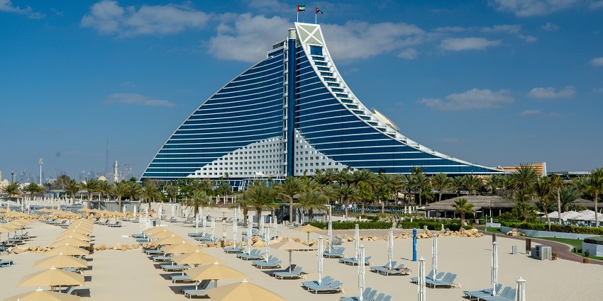 Jumeirah Beach with tall buildings rising in the background against a clear blue sky.