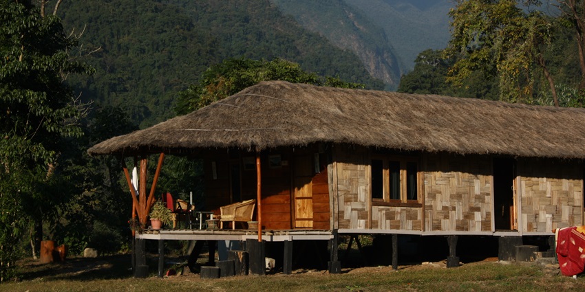 Image of a resort in a traditional hut style surrounded by lush green hills